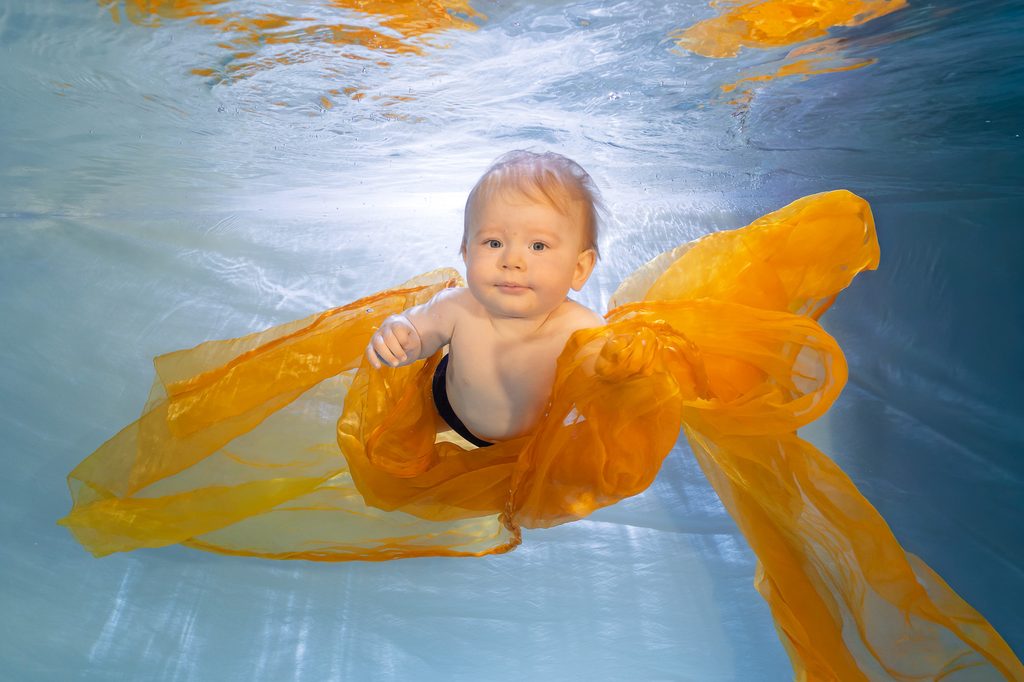 Profesionální podvodní foto miminka s&nbsp;oranžovou látkou v&nbsp;baby klubu